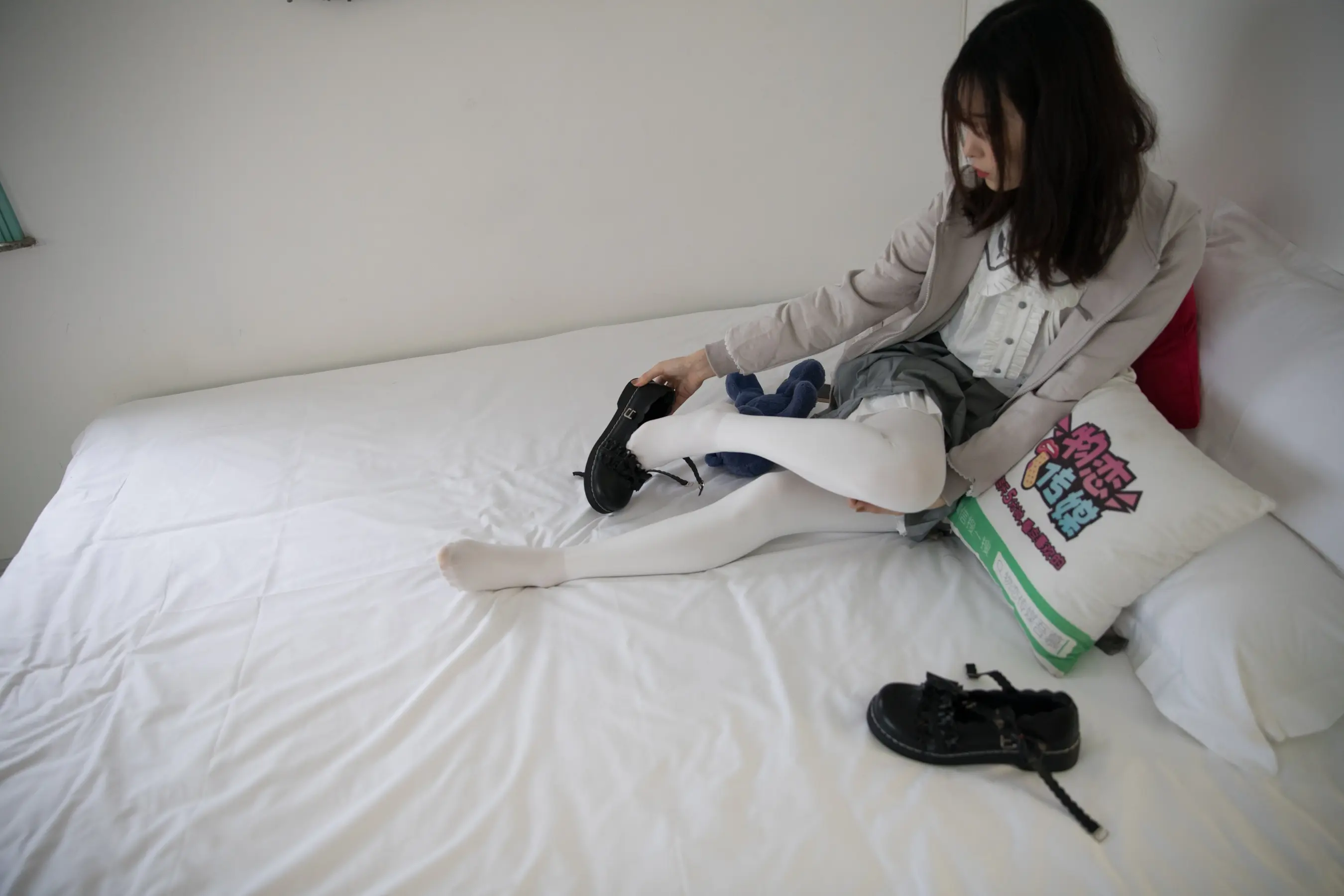 有一个女人坐在一张床上，床上有一个白色的枕头