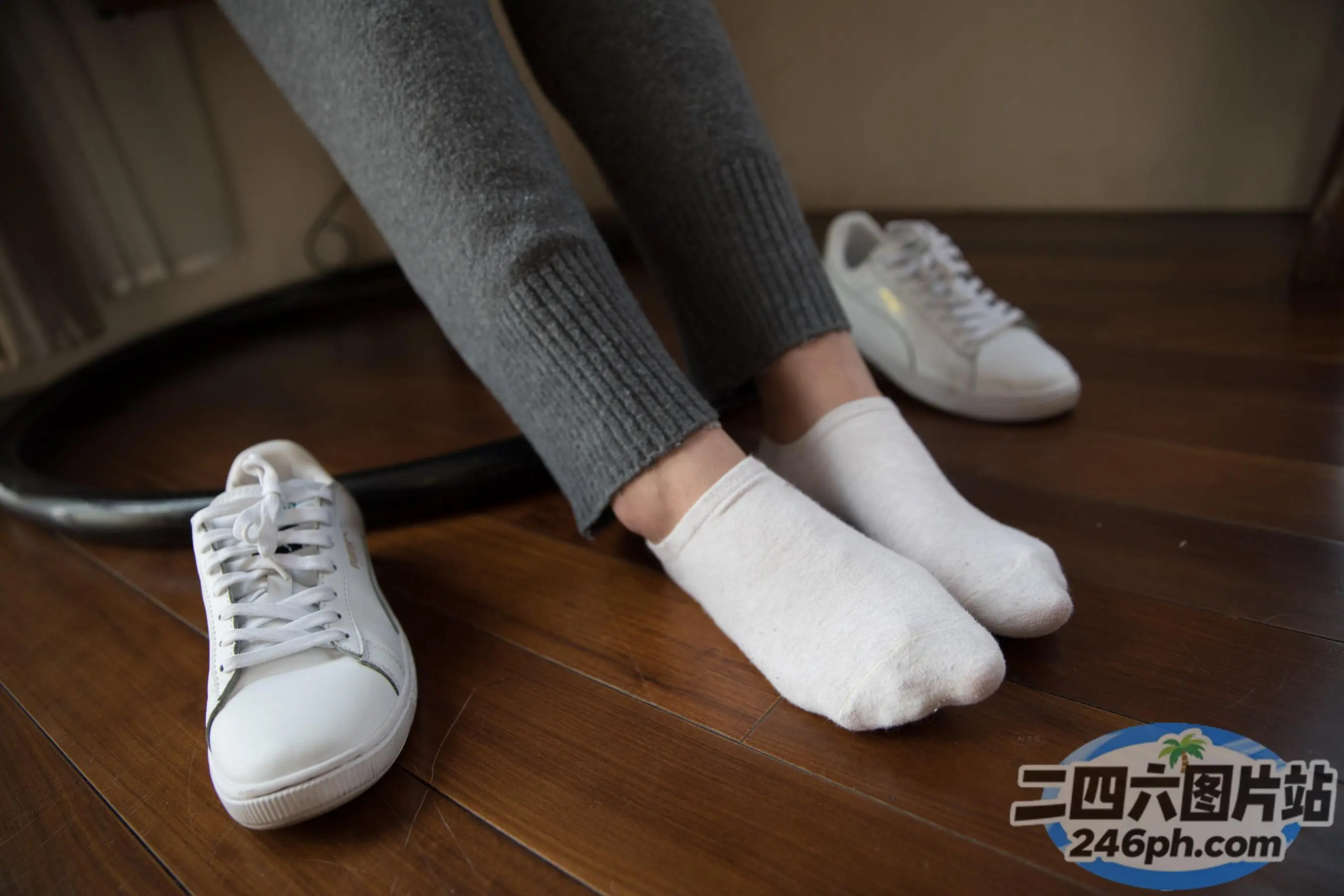 有人站在木地板上，脚踩着一双白色运动鞋