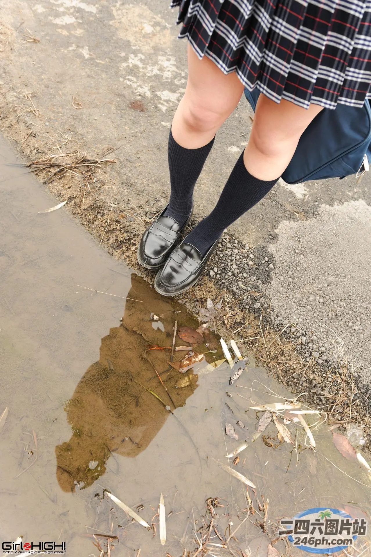 穿着裙子的双腿和站在水坑里的黑鞋