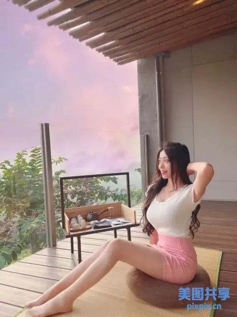 一个女人坐在阳台上的垫子上，可以看到风景