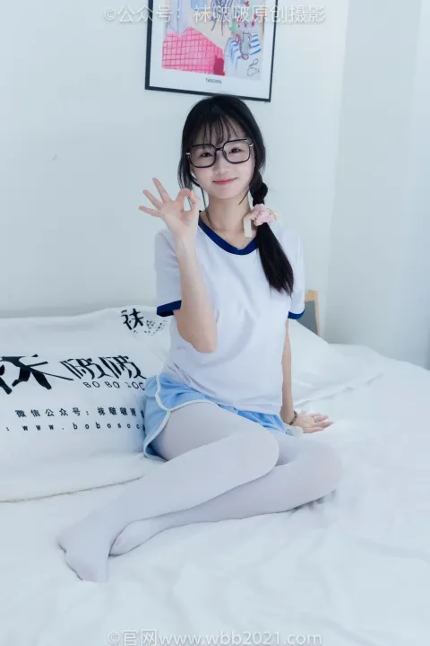 一个穿着白衬衫和蓝色裙子的女人坐在床上