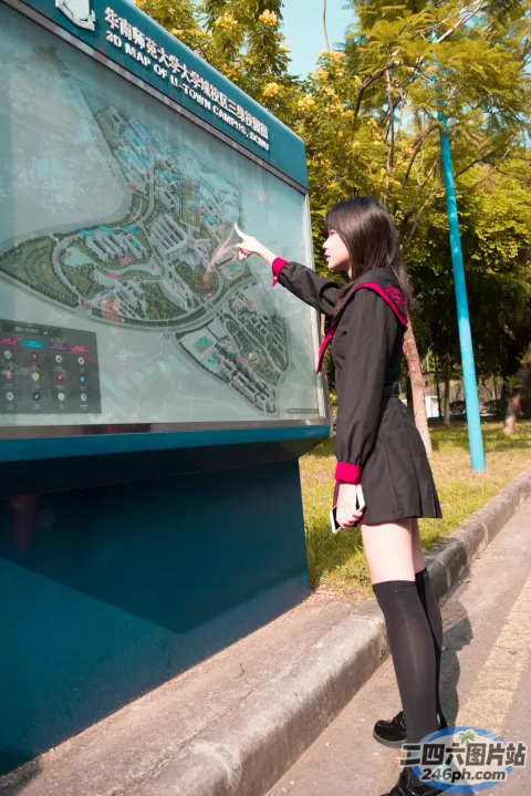 身穿黑色夹克的女子指着蓝色板上的地图