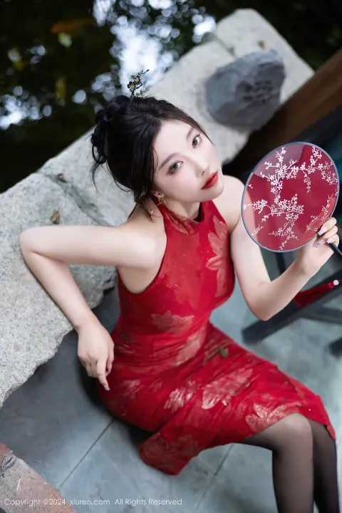身穿红裙的阿拉菲女子拿着镜子看着自己