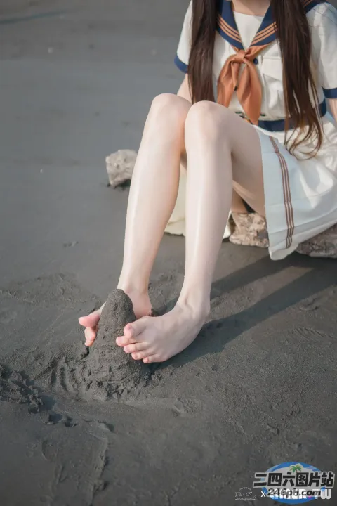 有一个女人坐在沙地上，她的脚踩在沙子里