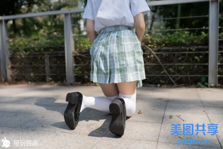 人行道上走着一个穿着裙子和袜子的女孩