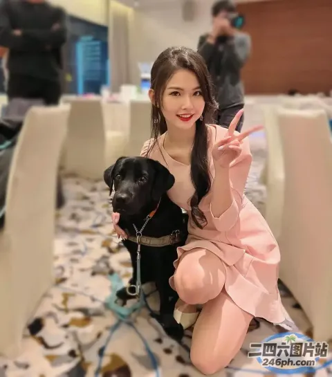穿着粉红色连衣裙的女人坐在地板上，面前有狗