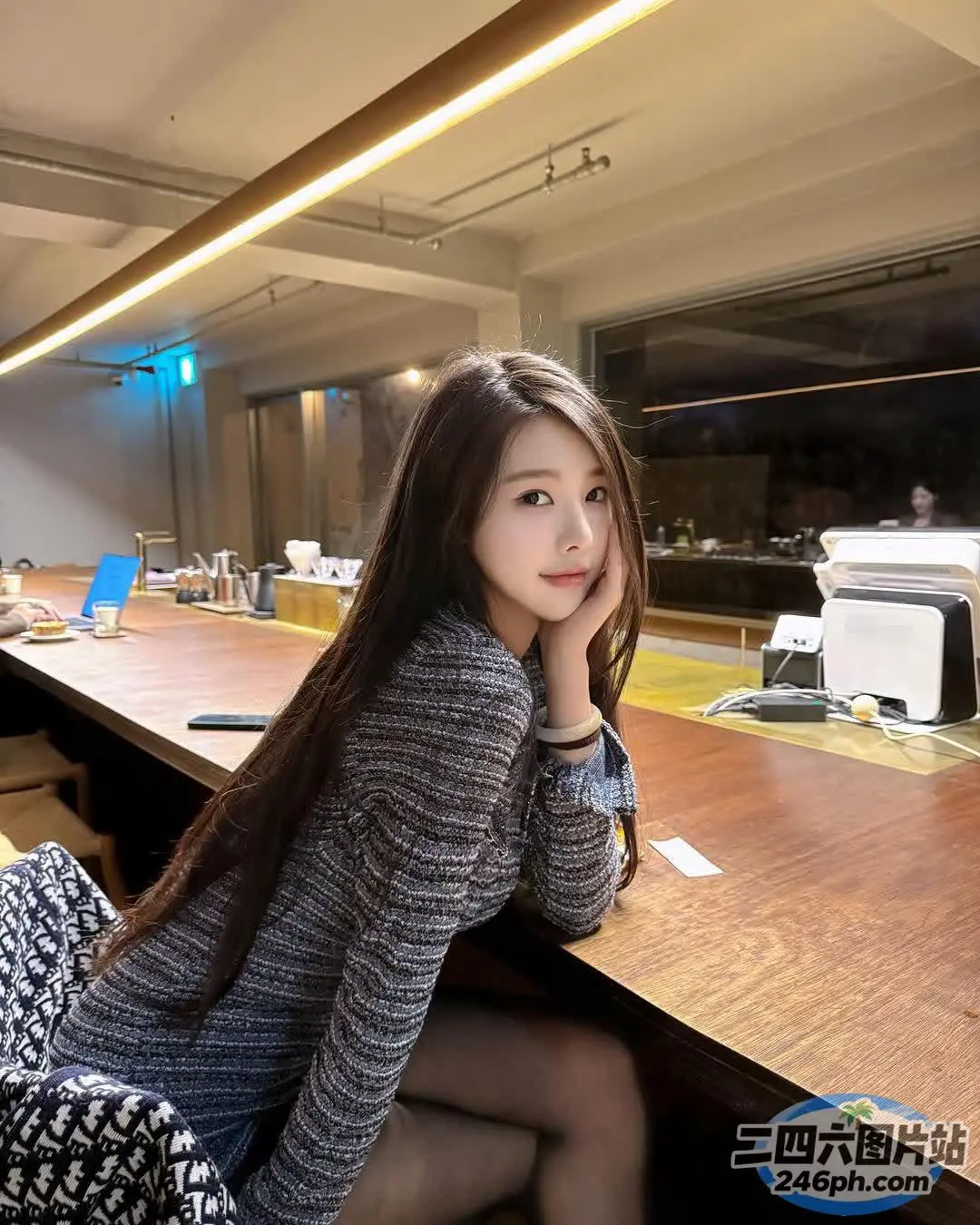有一位女士拿着笔记本电脑坐在桌子旁
