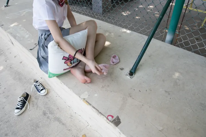 有一个年轻的女孩坐在地上，双脚抬起