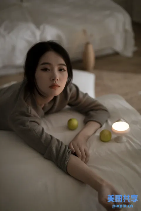 女人躺在床上，手里拿着两个苹果和一根蜡烛