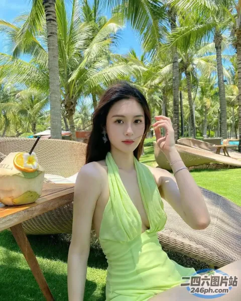 一位身穿绿色连衣裙的女子坐在草坪上的特写