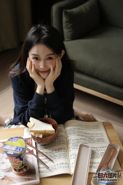 地板上坐着一个女人，手里拿着一本书和一碗食物