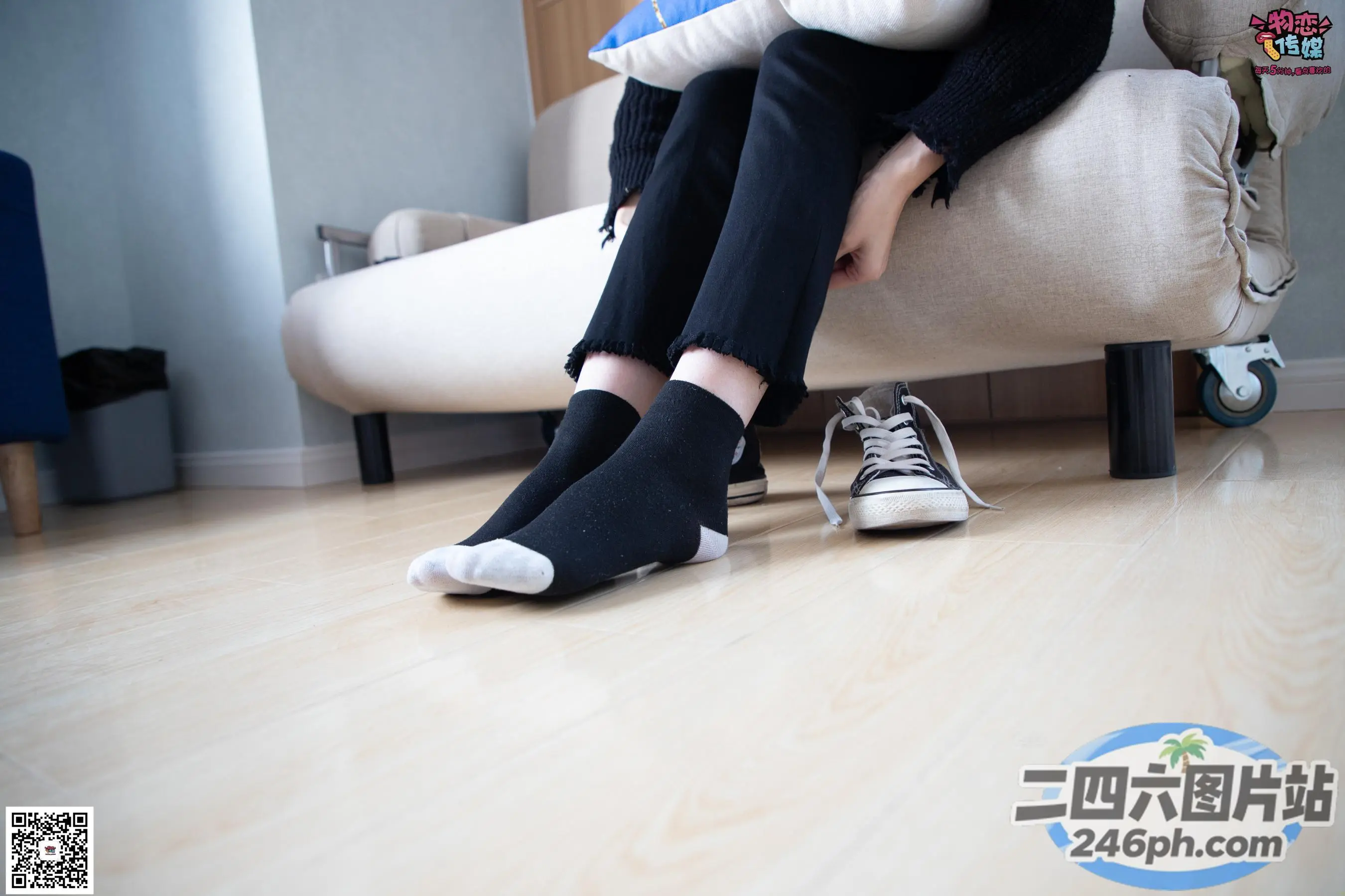 Araffe 坐在沙发上，手里拿着一双黑白运动鞋