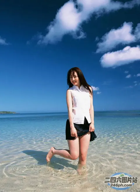 身穿白衬衫和黑色短裤的阿拉夫德女子站在浅水中