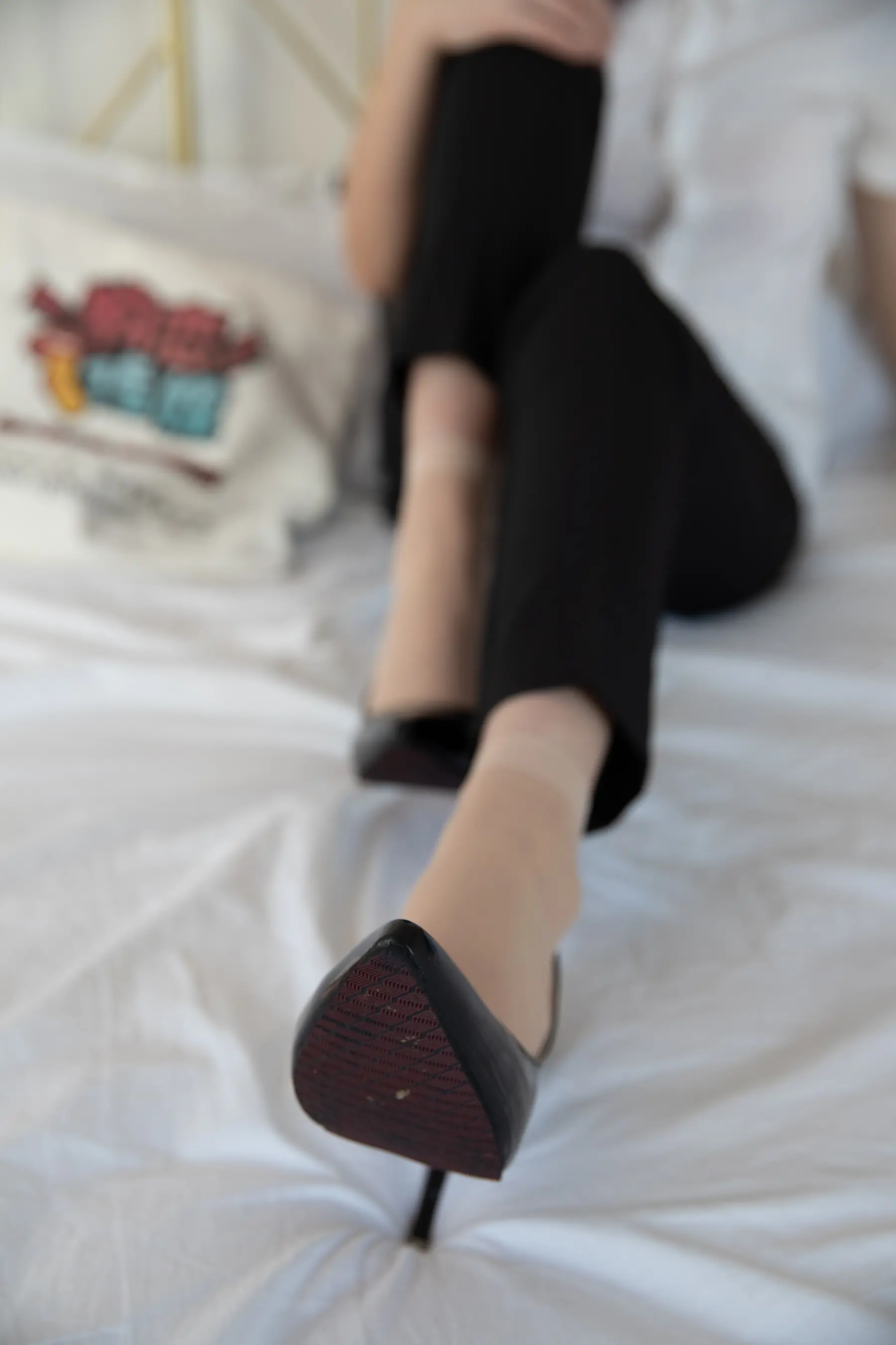 女人坐在床上，双腿交叉，双脚抬起