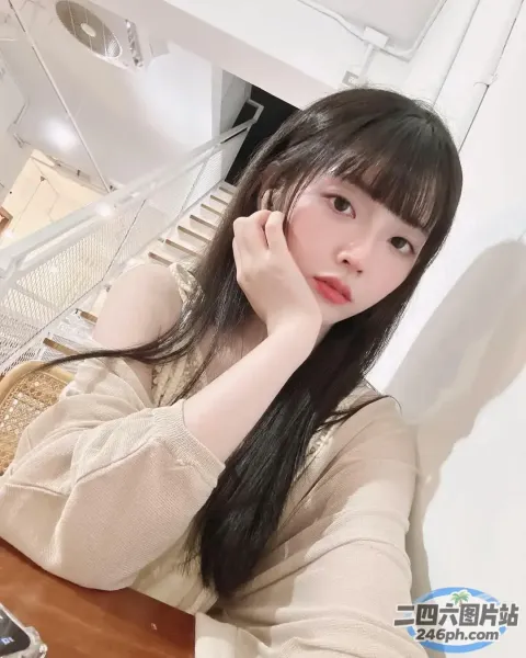 有个女人坐在桌子旁，手里拿着手机