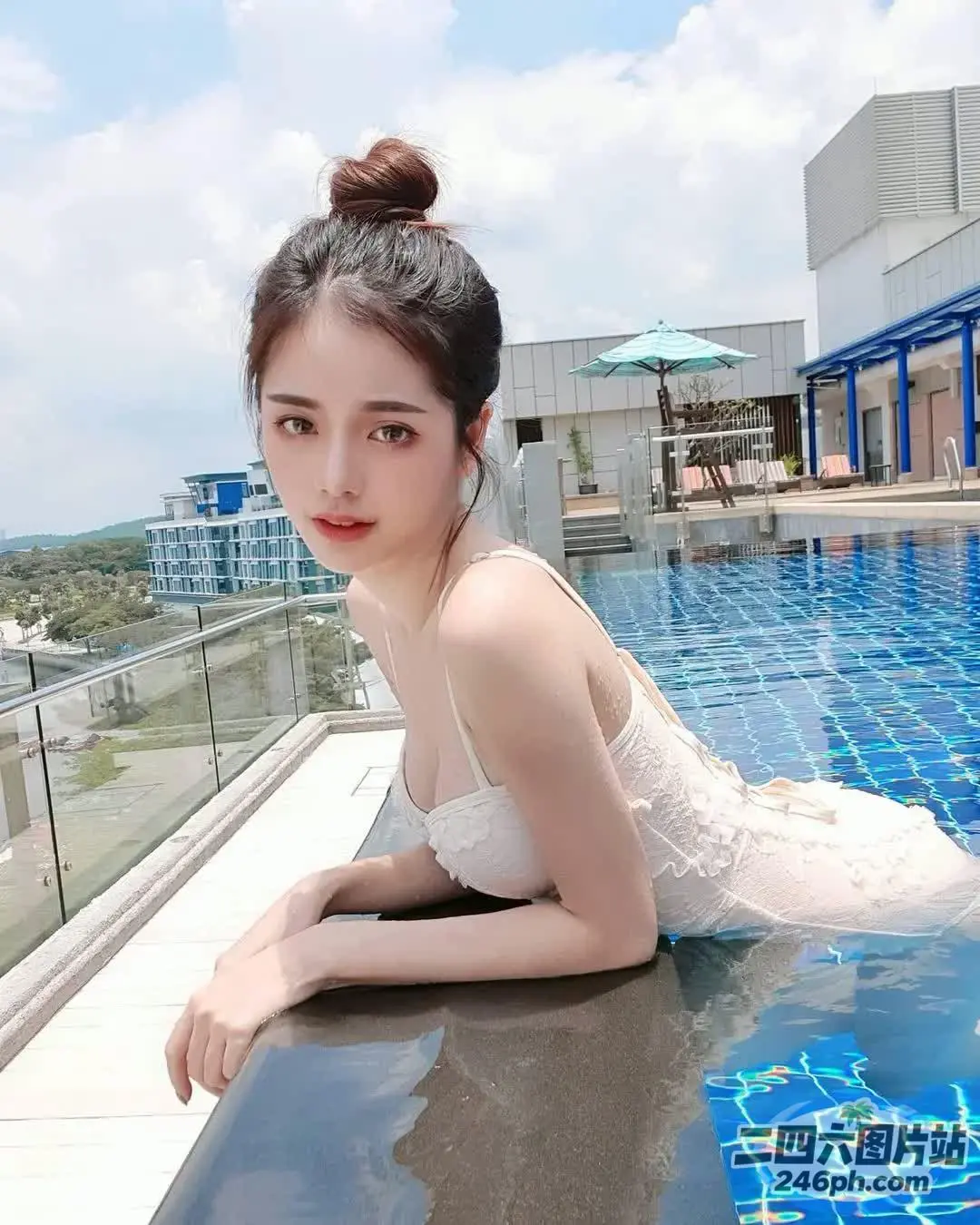 一个穿着白色连衣裙的女人躺在游泳池旁边的窗台上