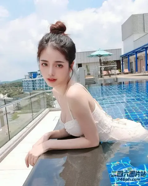 一个穿着白色连衣裙的女人躺在游泳池旁边的窗台上