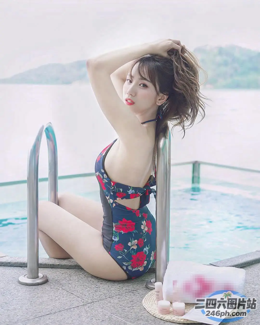 一个穿着花泳衣的女人坐在游泳池旁边的窗台上