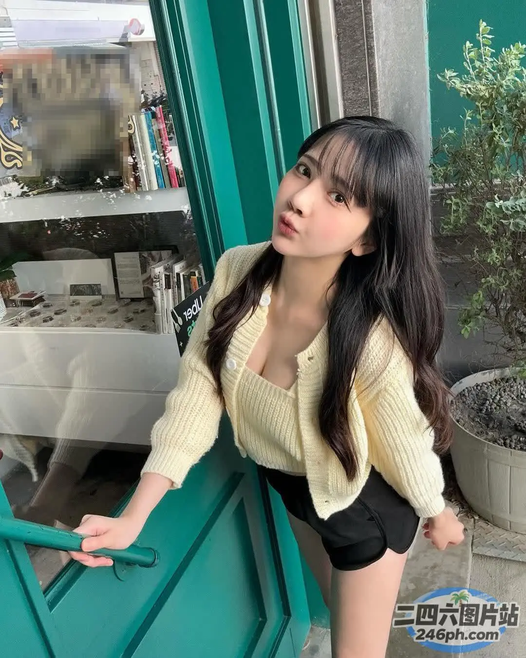 阿拉伯裔亚洲妇女靠在绿色的门上，附近有一只猫