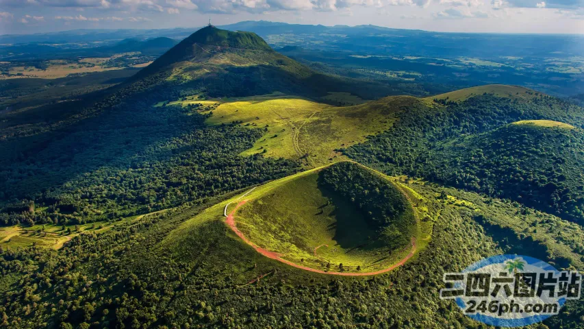 一座绿色山峰的鸟瞰图，红色的道路蜿蜒穿过它