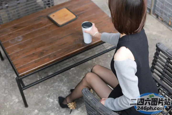有个女人坐在长凳上，手里拿着一杯咖啡