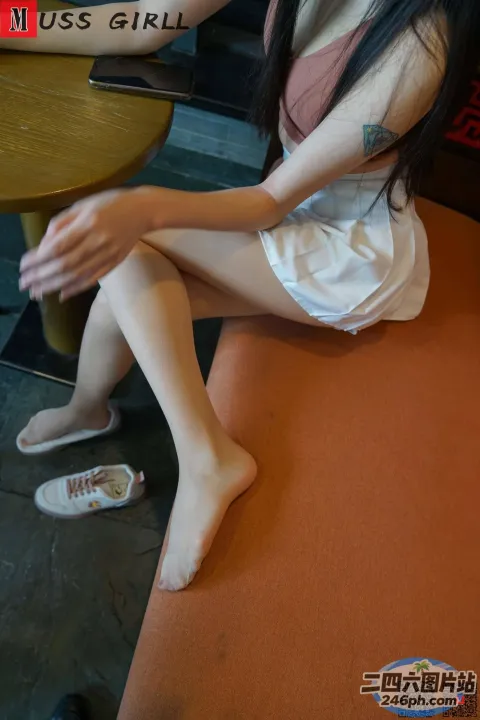 阿拉菲坐在桌子上，手里拿着一本书和一杯咖啡