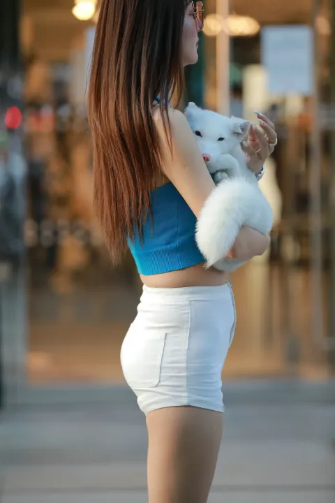 身穿蓝色上衣的 Araffe 女子，怀里抱着一只白狗