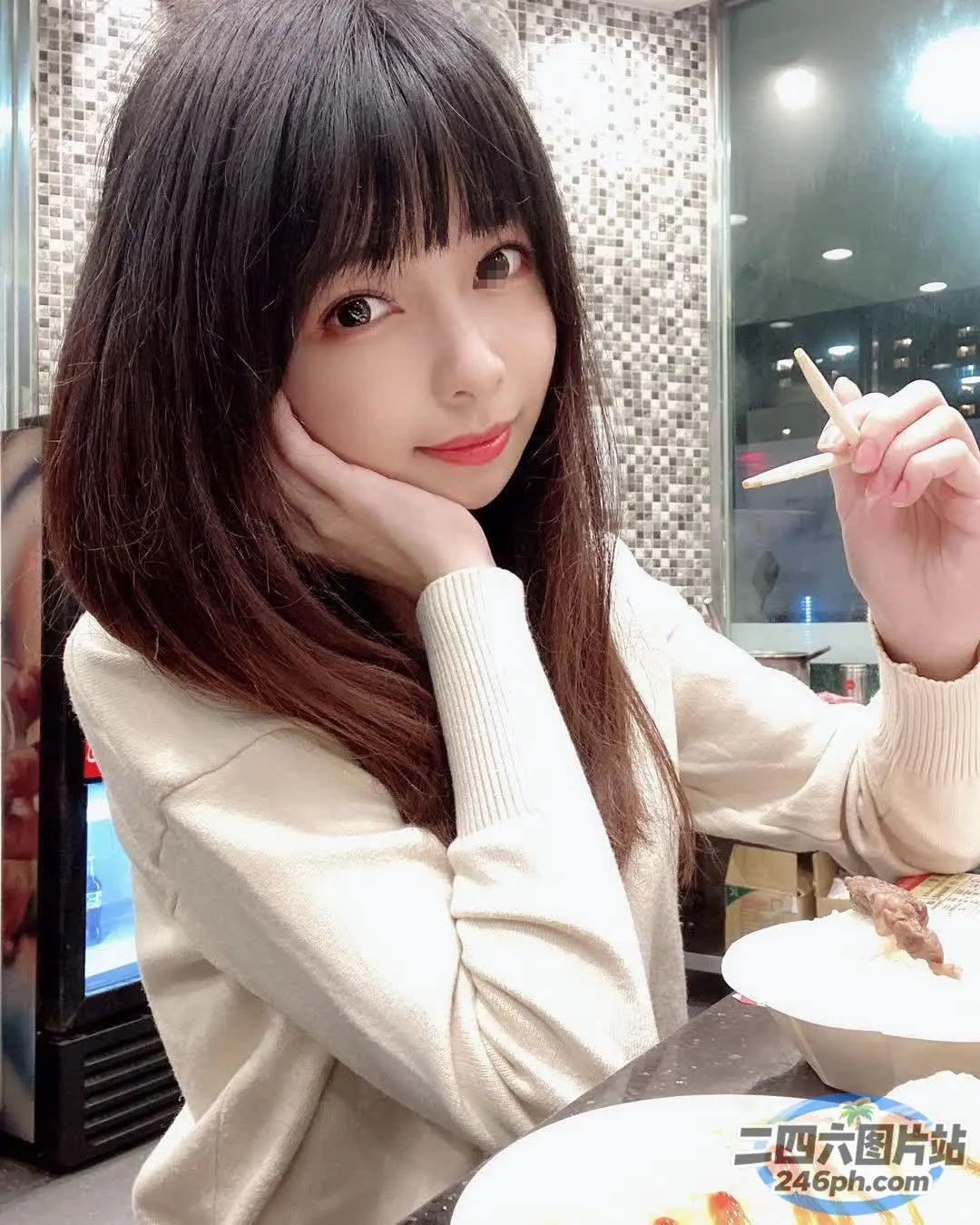 阿拉菲女人坐在桌子旁，手里拿着一盘食物和一把叉子