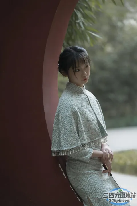 有个女人撑着伞站在墙边
