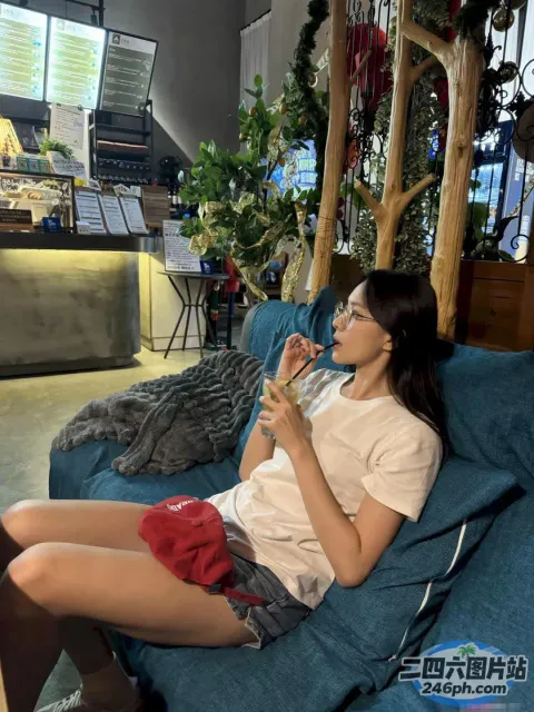 坐在沙发上喝一杯水的女人
