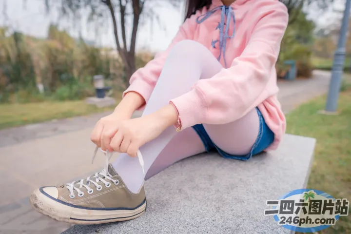 有一个女人坐在长凳上系鞋带