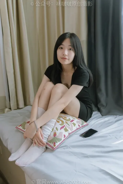 阿拉夫德女人坐在床上，手里拿着枕头和手机