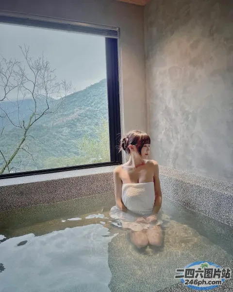 有一位女士坐在浴缸里，可以看到山景