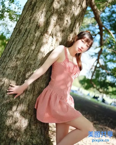 穿着粉红色连衣裙靠在树上的阿拉夫德亚洲女子