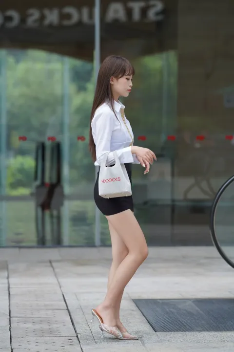 拿着钱包和鞋子走在街上的阿拉菲女人