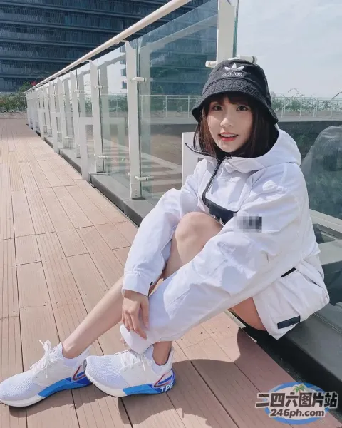 一名女子坐在玻璃墙旁边的木地板上