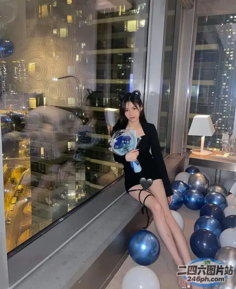 有一个女人坐在窗台上，手里拿着一个蓝白相间的球