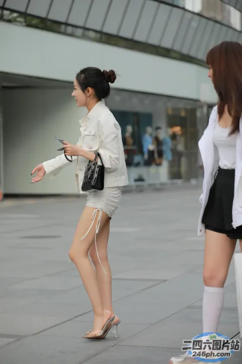 身穿白衬衫和黑色裙子的女子走在人行道上