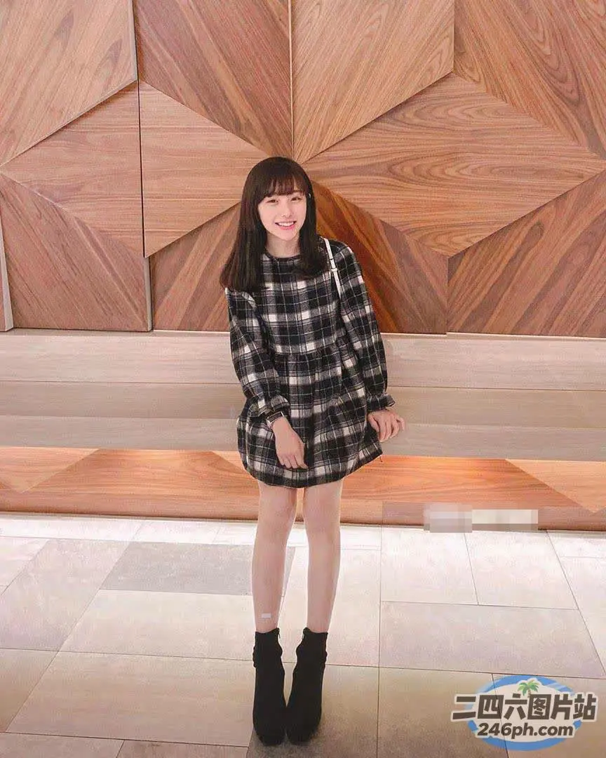 身穿格子裙和黑色靴子的阿拉菲德女孩站在木墙前