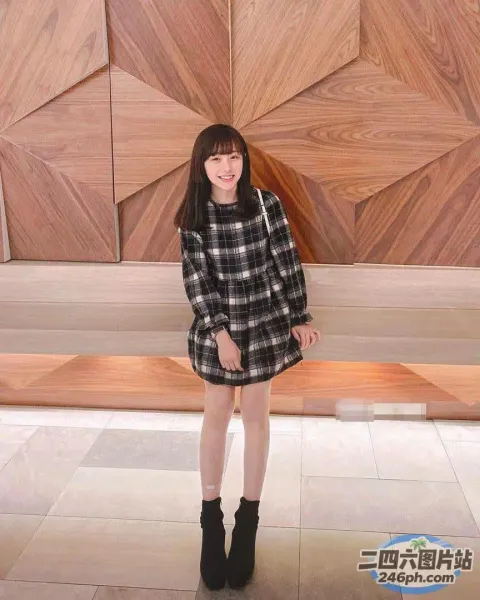 身穿格子裙和黑色靴子的阿拉菲德女孩站在木墙前