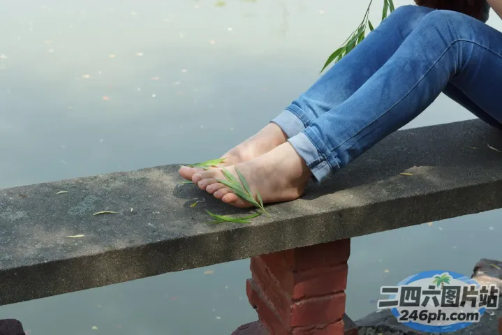 有人坐在长凳上，双脚踩在水边