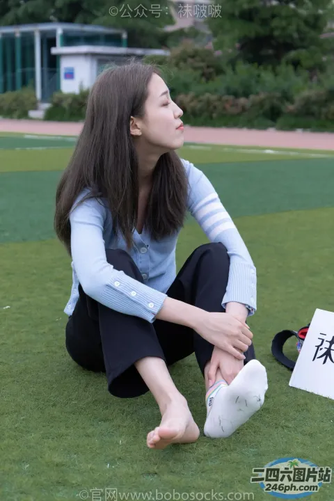 阿拉费德女人坐在草地上，手里拿着一个牌子