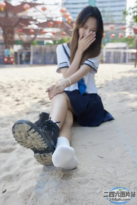 有一个女人坐在沙滩上，双脚抬起