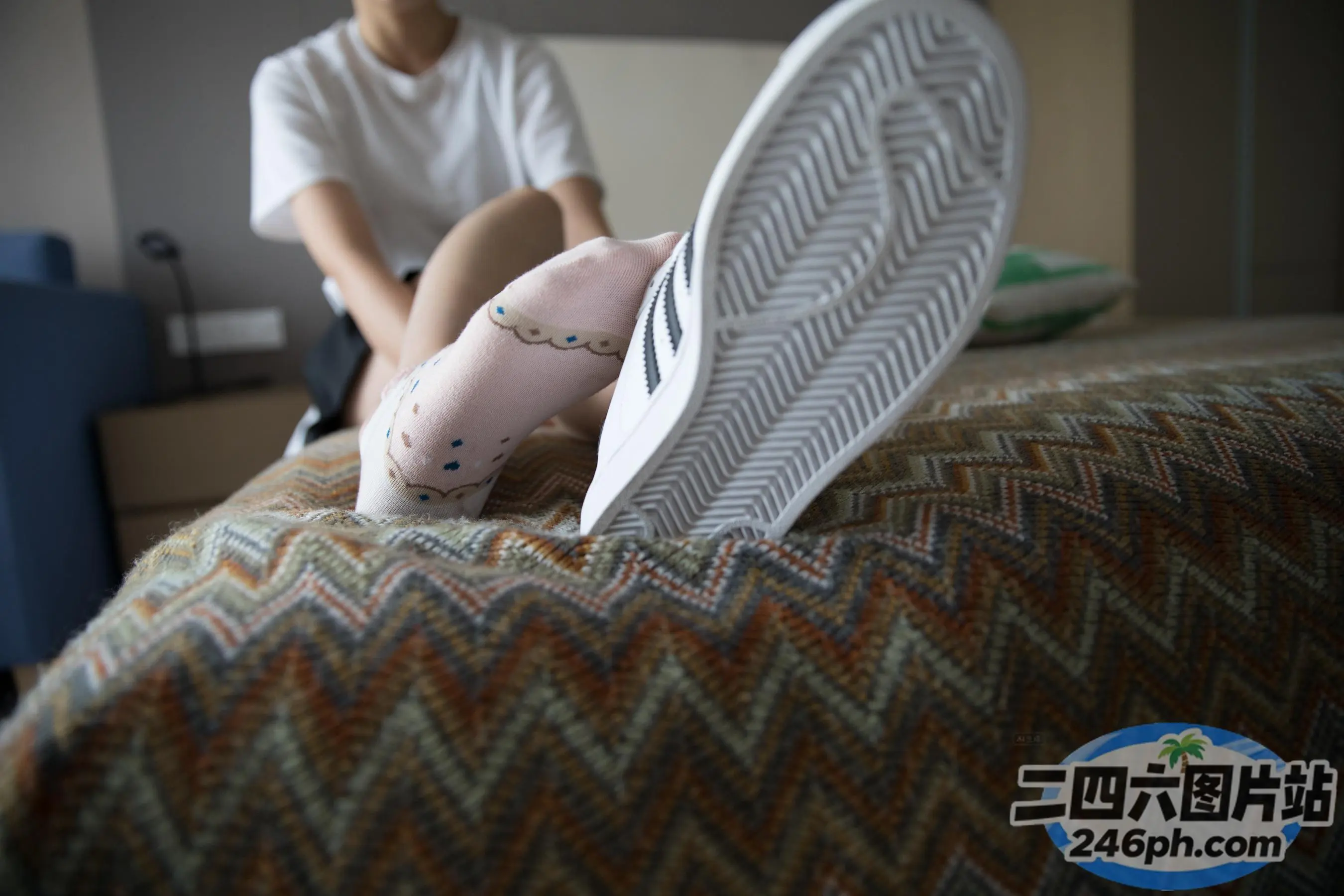 有人坐在床上，双脚抬起，一个人坐在床上