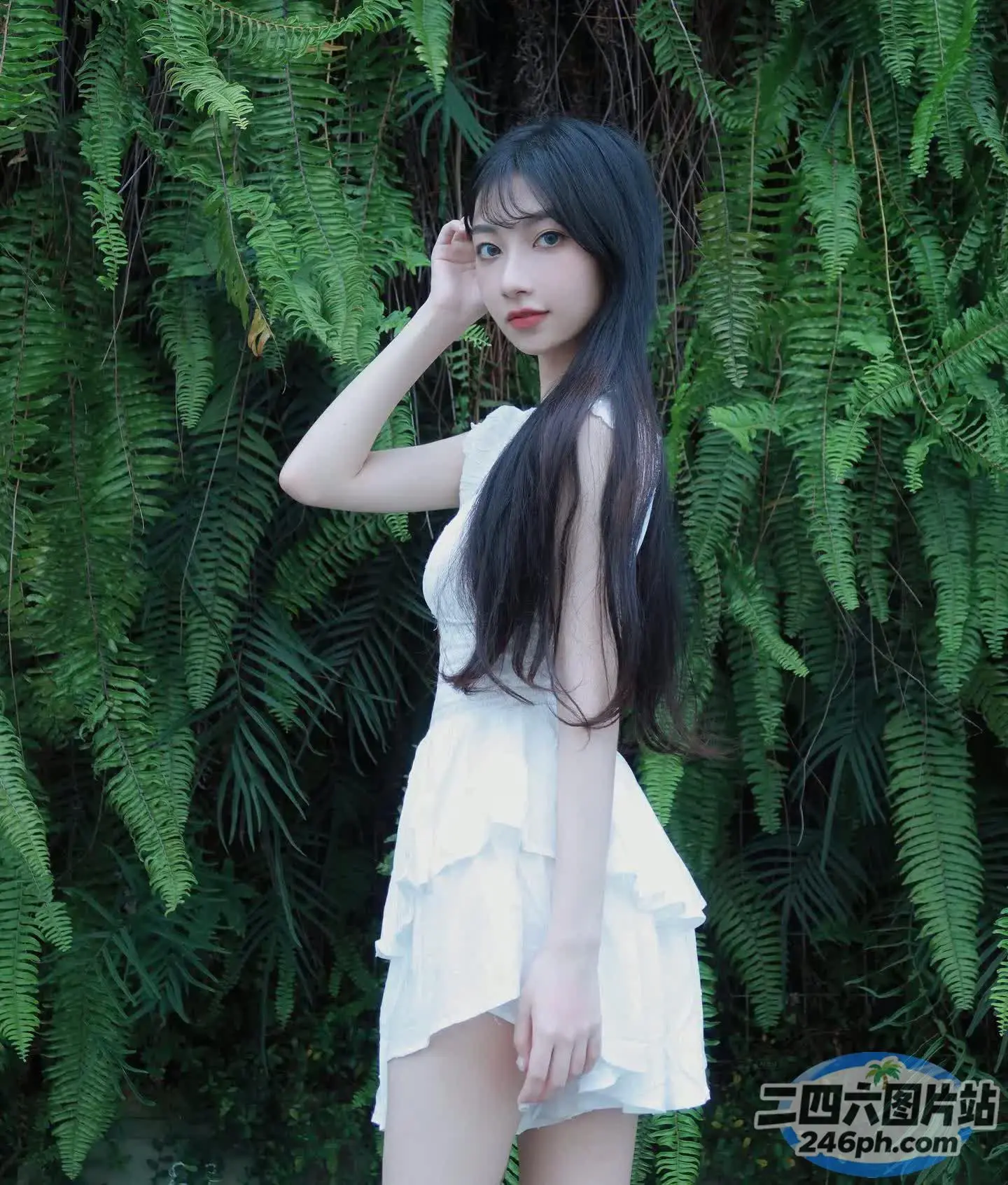 身穿白色连衣裙的阿拉伯女郎在灌木丛前摆姿势