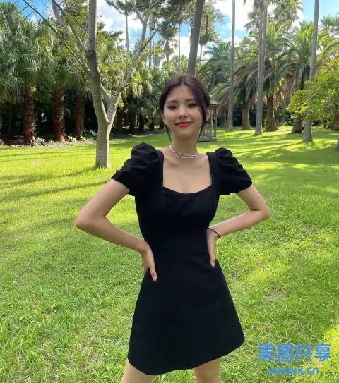 一个穿着黑色连衣裙的女人站在草地上