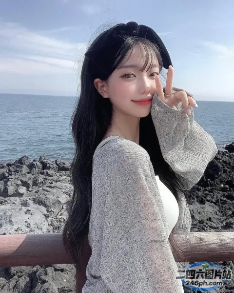 黑发长发的 Araffe 女人在岩石海滩上摆姿势