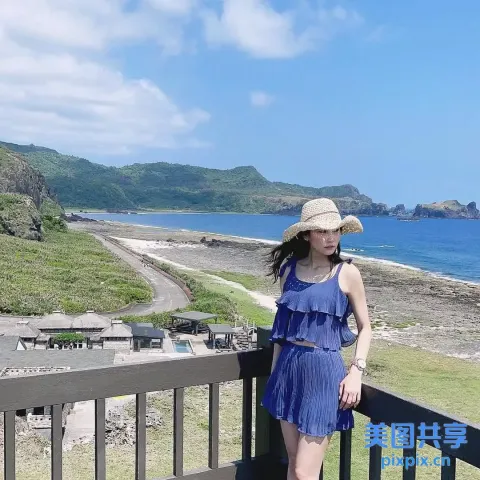 身穿蓝色连衣裙、戴着帽子的 araffe 女子站在阳台上