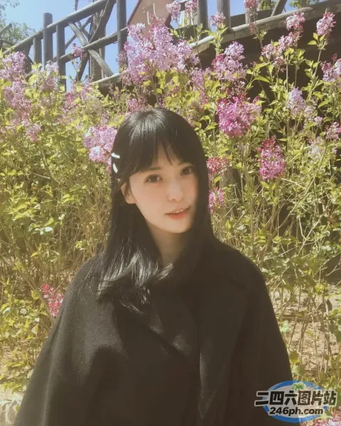 黑长发、黑外套的阿拉菲女人站在一丛花前