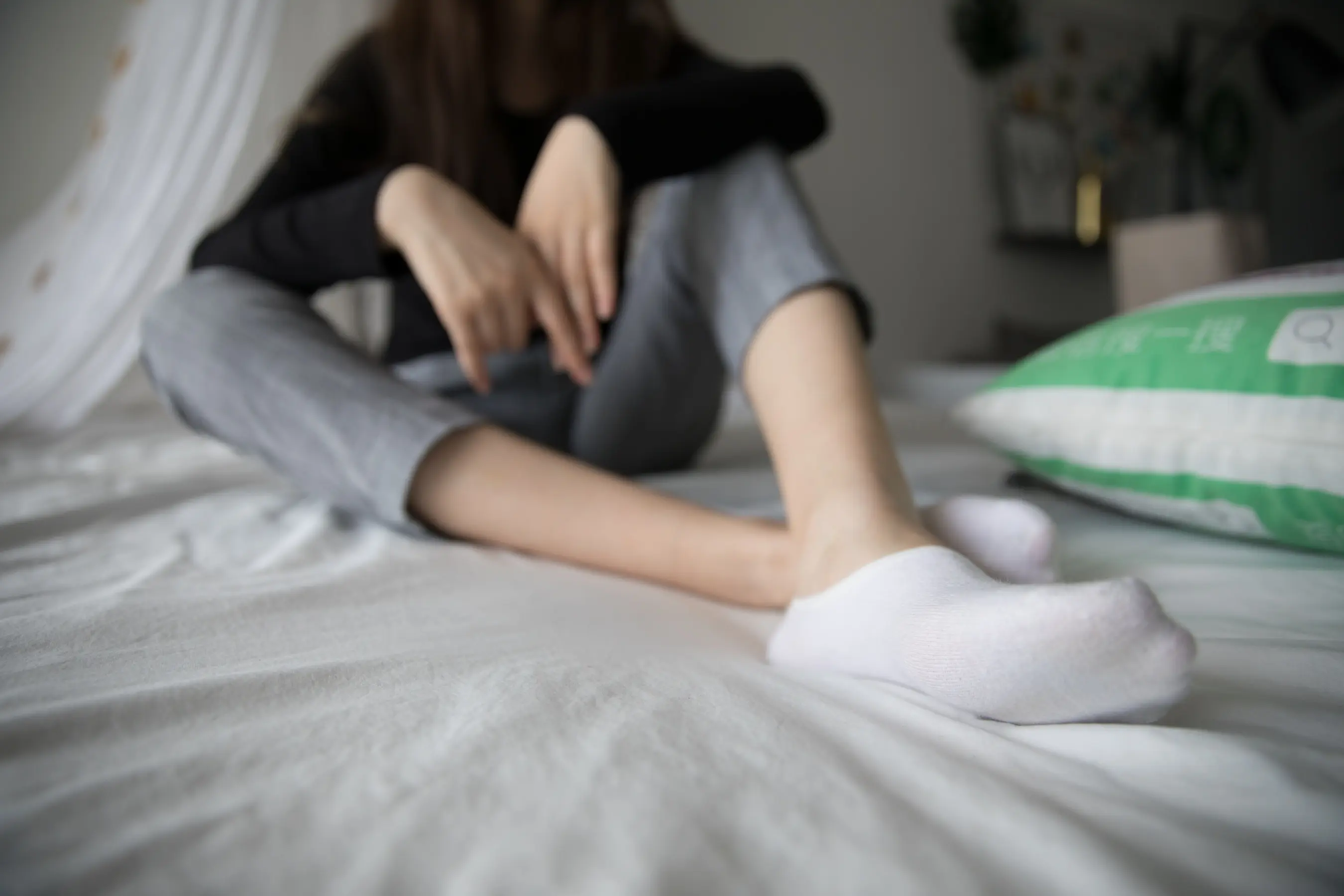 有一个女人坐在床上，双脚抬起